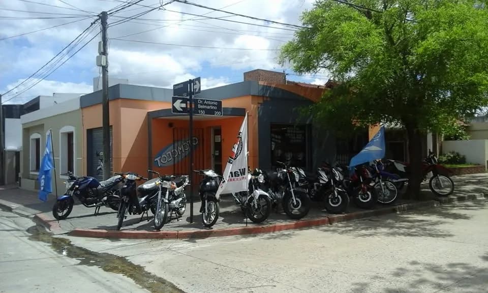 Esquina de TodoMoto con motos exhibidas en la vereda y banderas de la marca