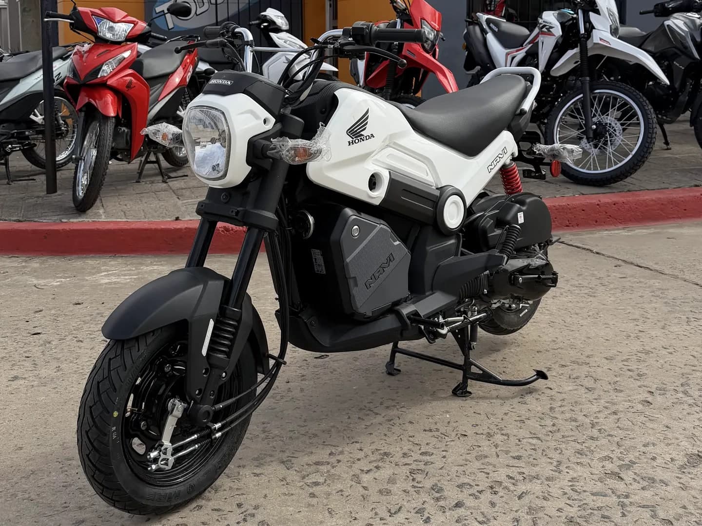 Honda Navi 110 0 km blanca y negra, vista lateral derecha en el salón de TodoMoto